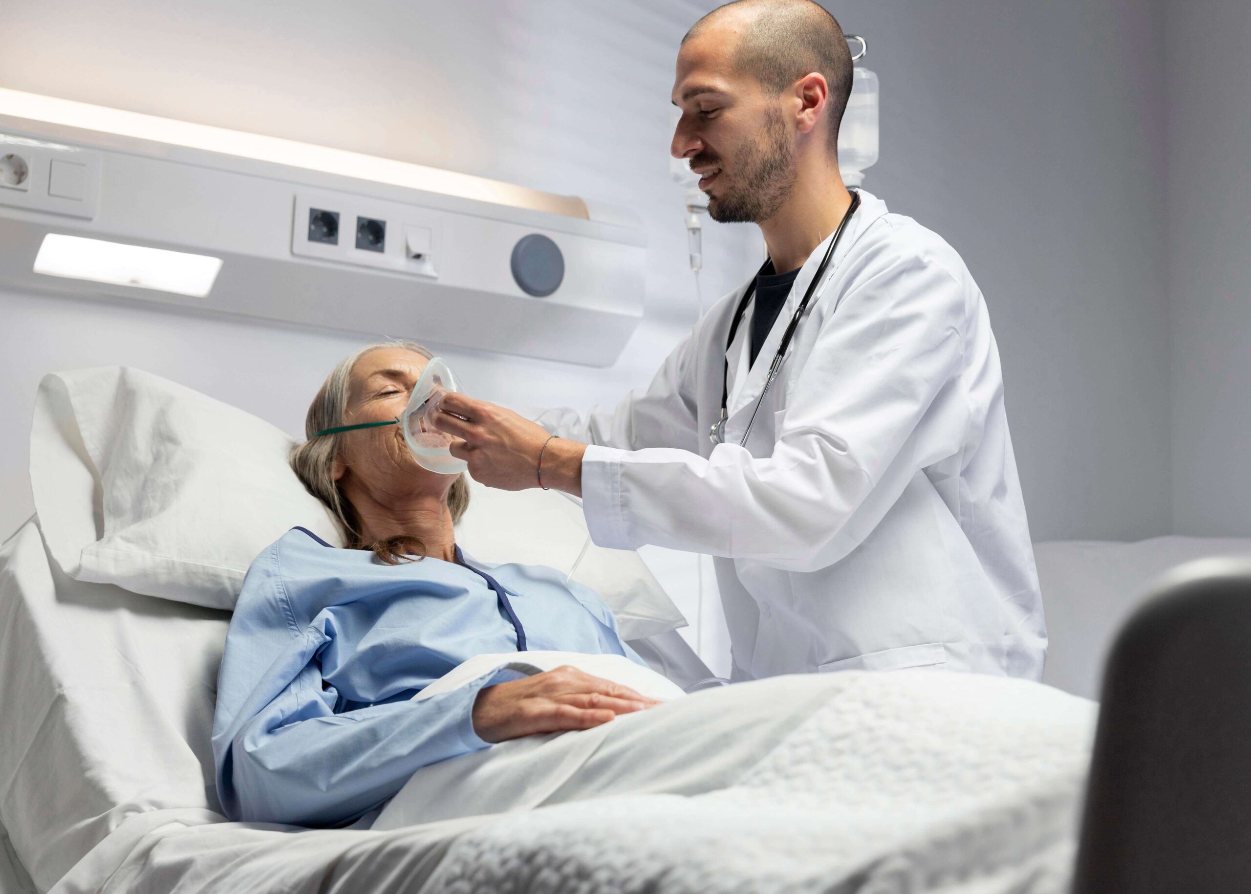 Healthcare provider assisting a patient with oxygen support in a clinical setting.