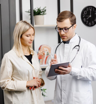 doctor explaining medication details on a tablet to a patient, assisting her with information about Oxybutynin HCL 5mg for managing overactive bladder.