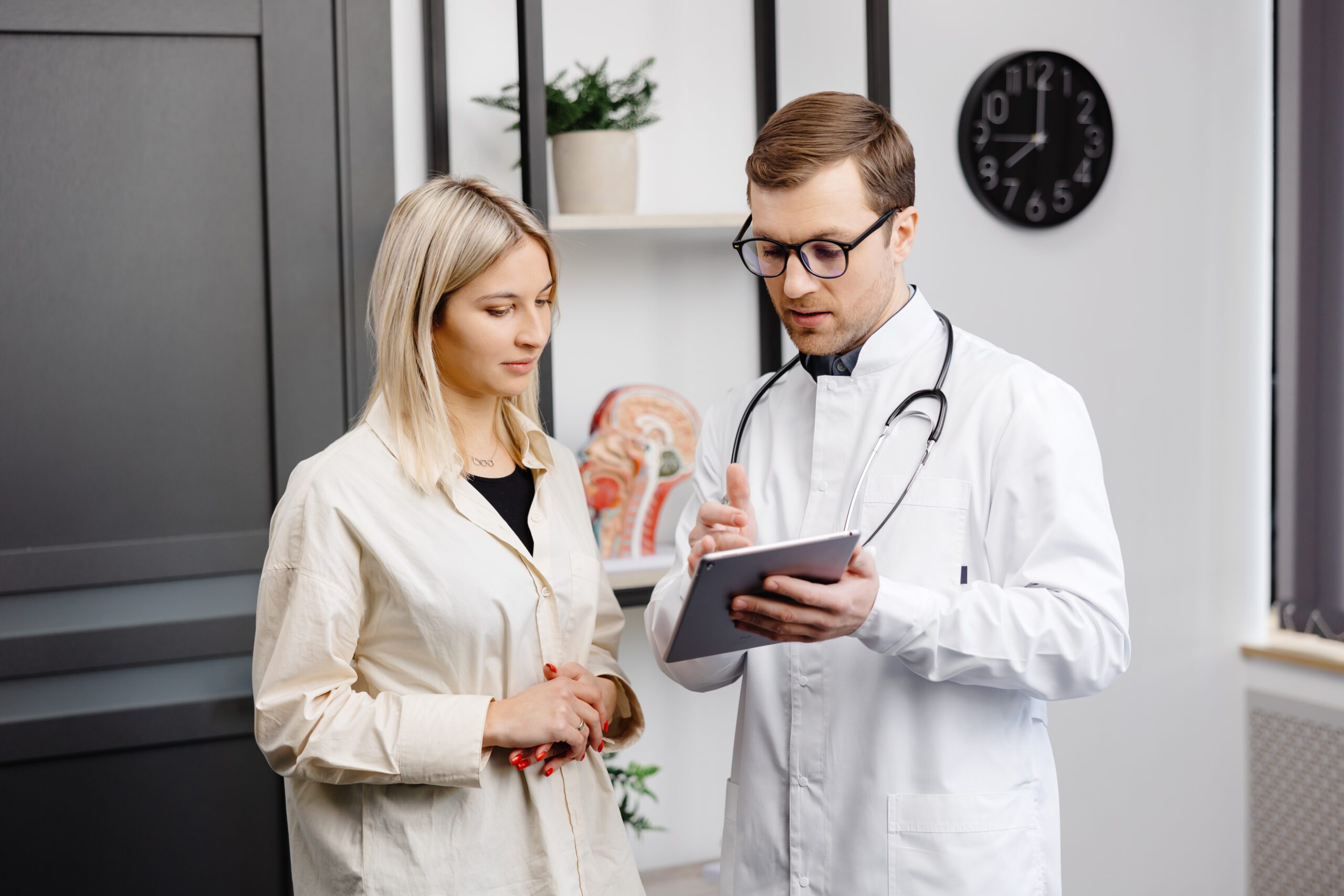 doctor explaining medication details on a tablet to a patient, assisting her with information about Oxybutynin HCL 5mg for managing overactive bladder.