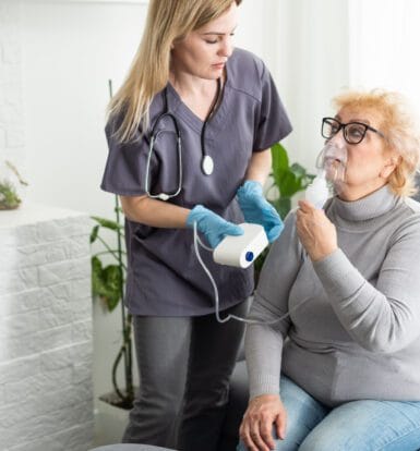 Nurse assisting an elderly patient with a nebulizer for respiratory treatment, highlighting the importance of prior authorization for respiratory medications like Air Suppress Aerosol.