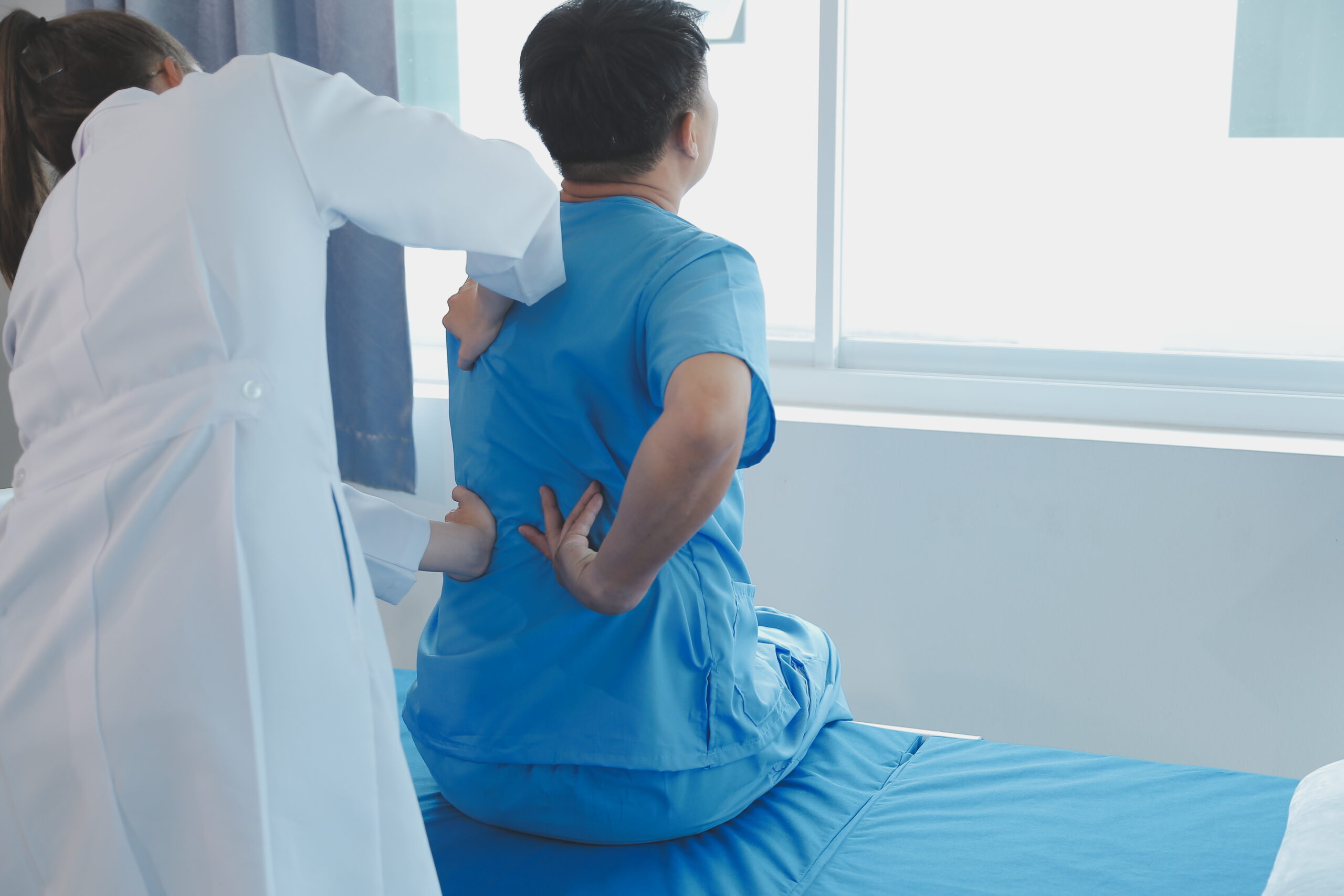 Doctor assisting a patient experiencing chronic back pain, illustrating the need for pain management solutions like Hydromorphone.