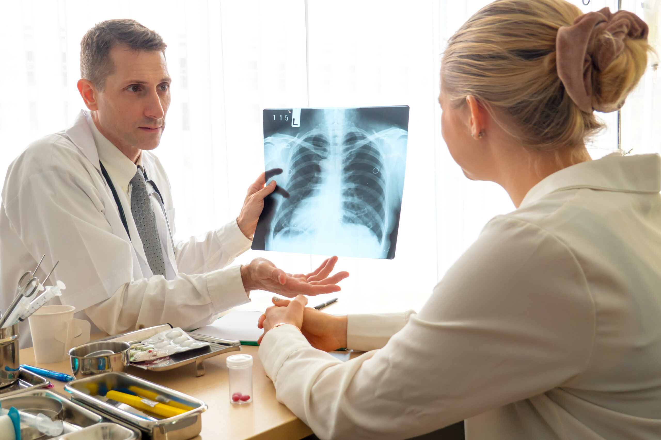 A healthcare provider showing a patient a chest X-ray image during a discussion about COPD treatment options and the necessity for prior authorization of Razor Powder with Sunshine Health Plan.