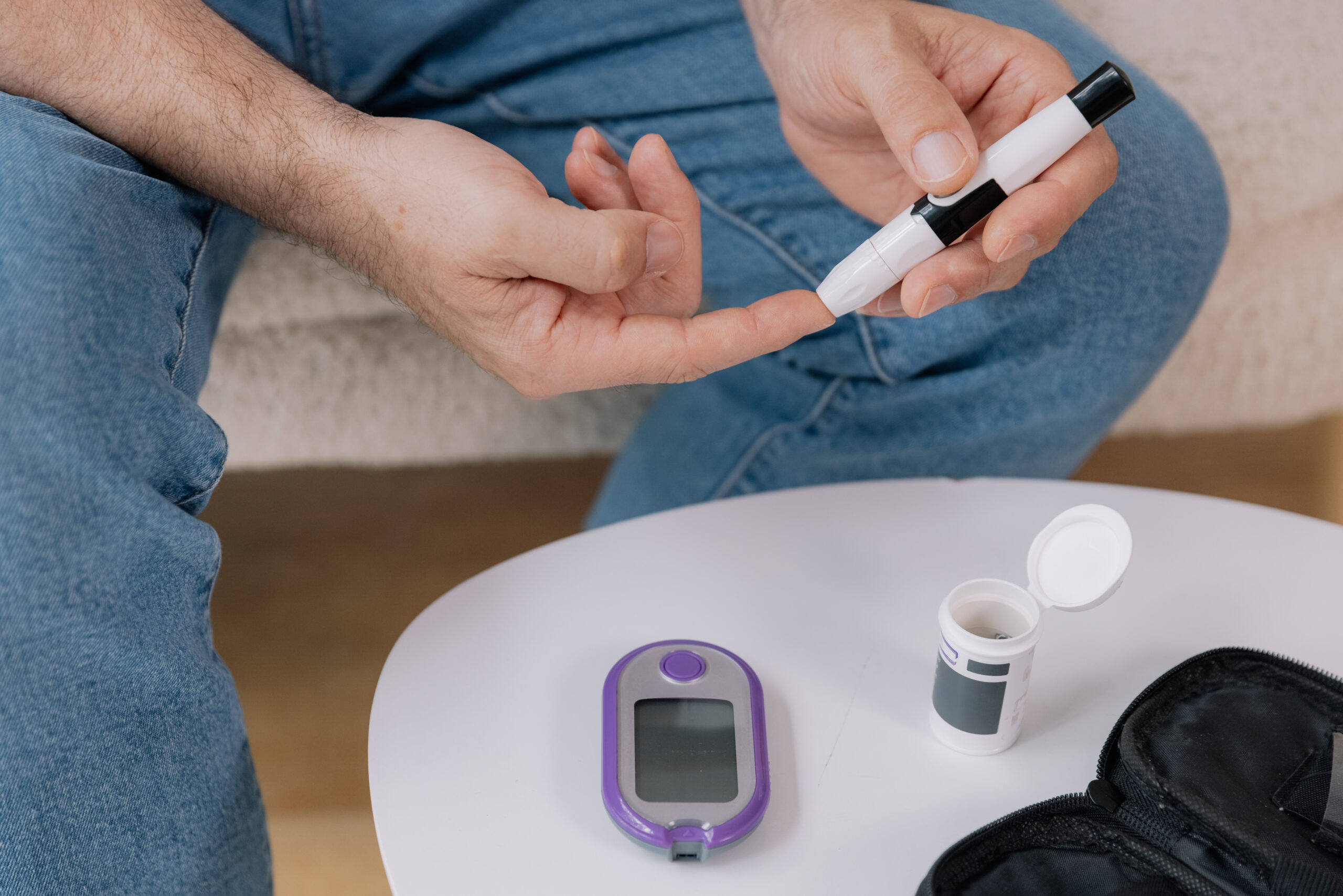 rson using a safety pen needle for diabetes management, showing the process of blood glucose testing.