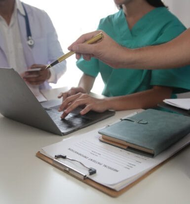 A medical coder reviewing patient records and using coding software to ensure accuracy in healthcare reimbursement.