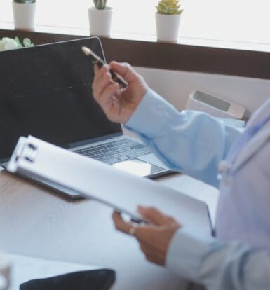 Healthcare provider working with a medical scribe who is documenting patient information on a computer.