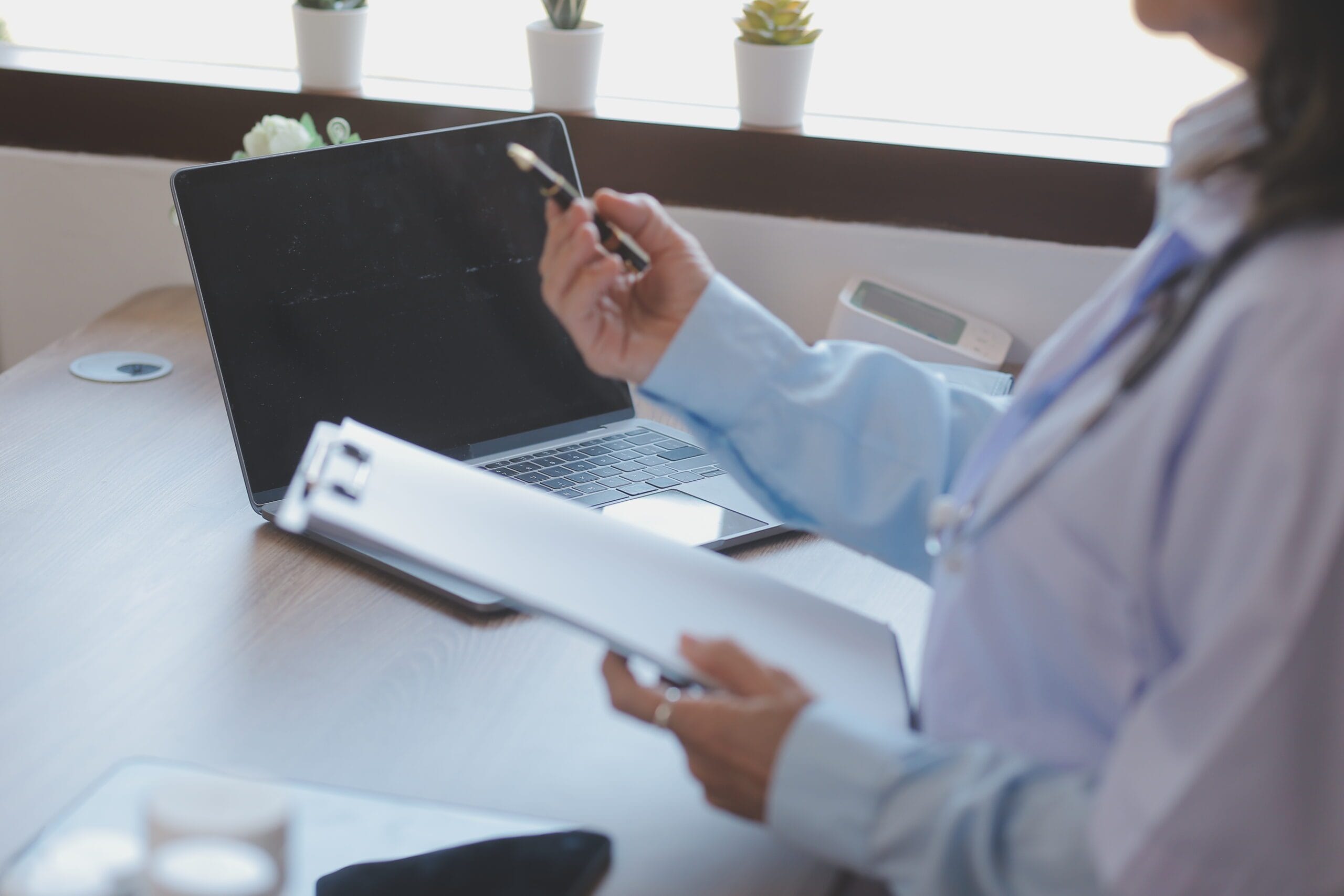 Healthcare provider working with a medical scribe who is documenting patient information on a computer.