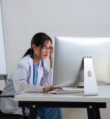 A healthcare provider interacting with a patient, while a medical scribe documents the visit in real time.