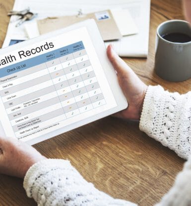 Person reviewing a health records checklist on a tablet, showing various medical check-up tasks and statuses.