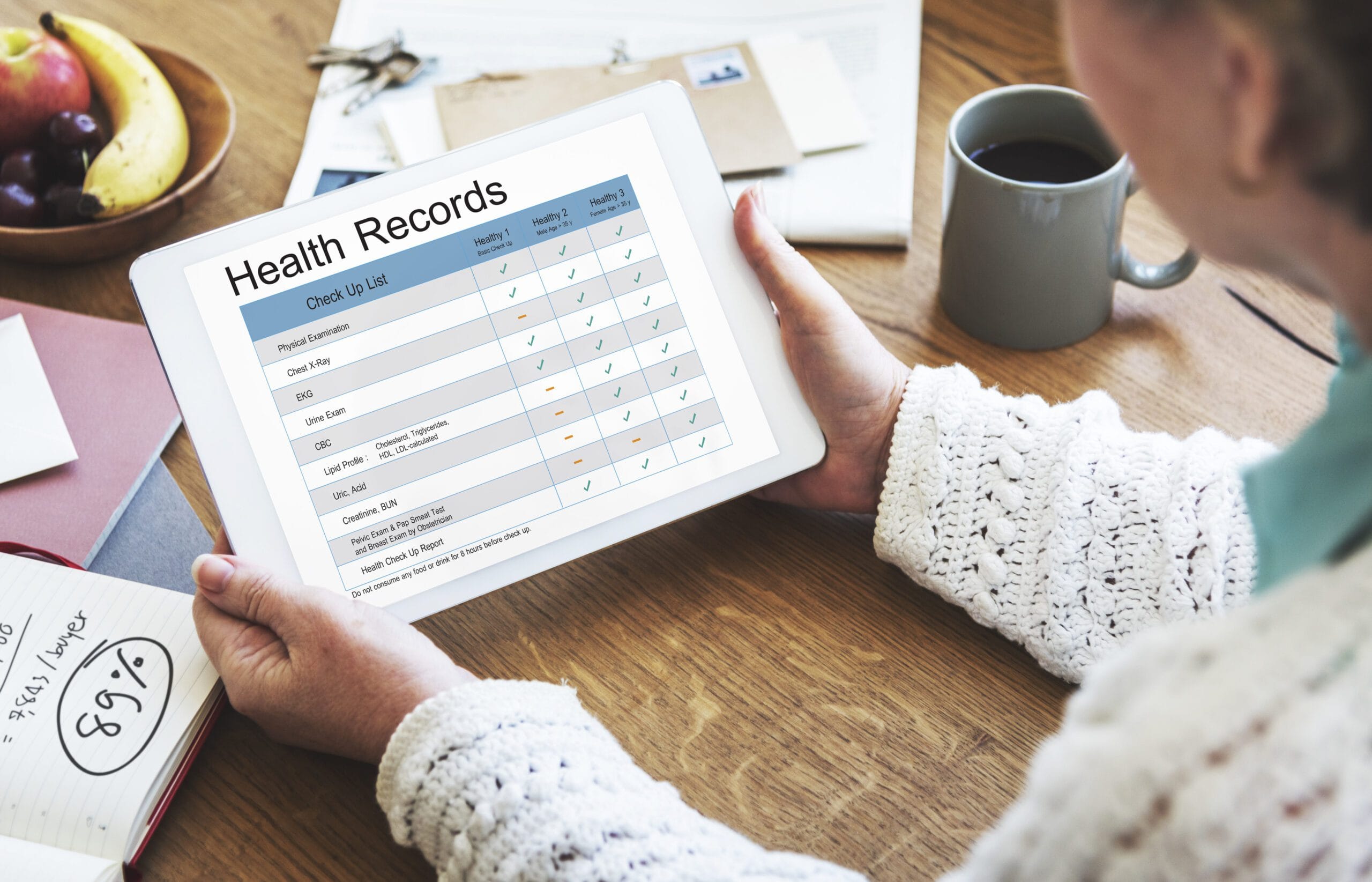 Person reviewing a health records checklist on a tablet, showing various medical check-up tasks and statuses.