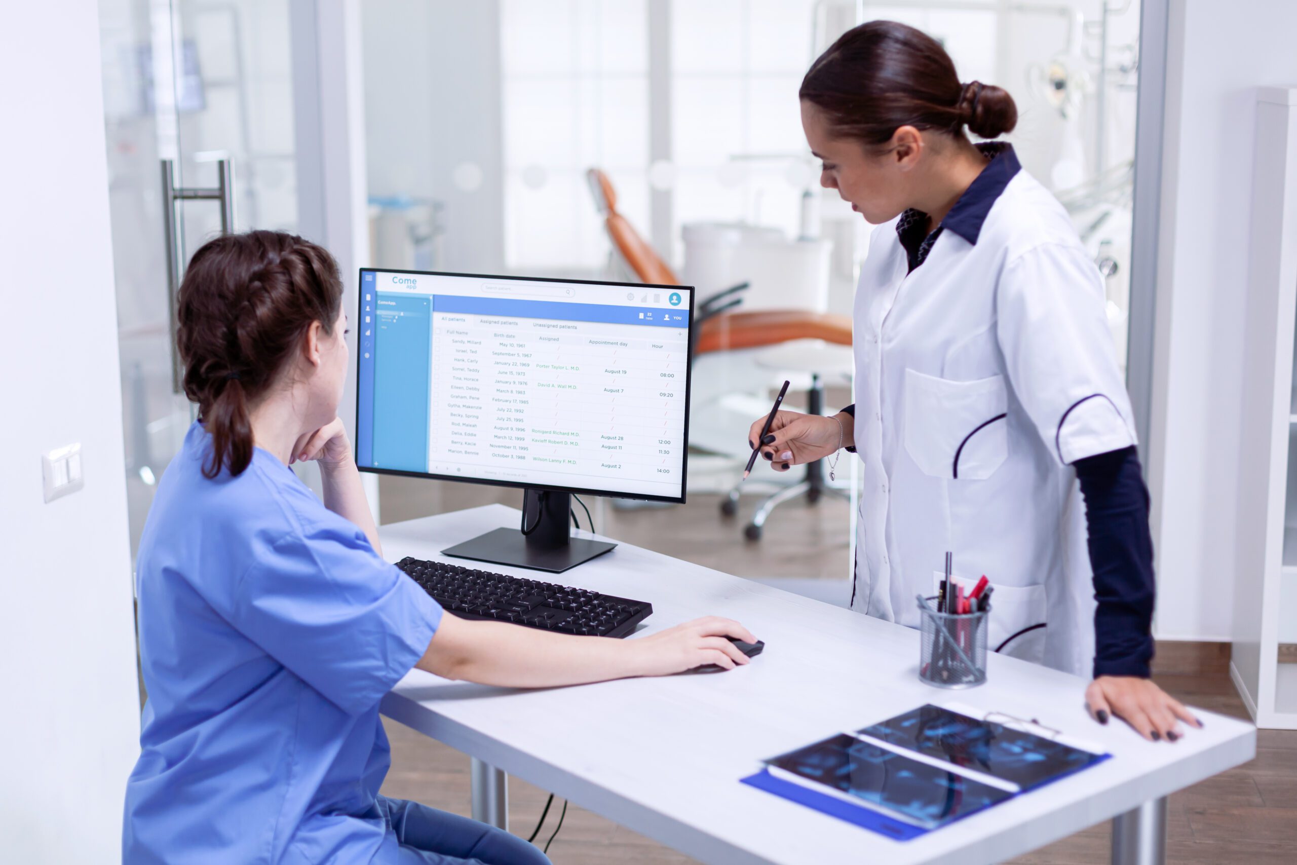 Two healthcare professionals discussing patient data on an EHR system, representing the role of technology in medical documentation.