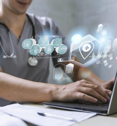 A healthcare provider typing on a laptop with holographic medical icons representing technology in medical scribing and coding.