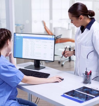 Two healthcare professionals reviewing patient information on a computer, representing the role of Virtual Medical Assistants in supporting small clinics with patient care and administrative tasks