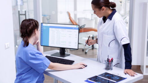 Two healthcare professionals reviewing patient information on a computer, representing the role of Virtual Medical Assistants in supporting small clinics with patient care and administrative tasks