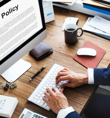 Person typing on a keyboard with an insurance policy displayed on a computer screen, symbolizing insurance verification in healthcare revenue cycle management.