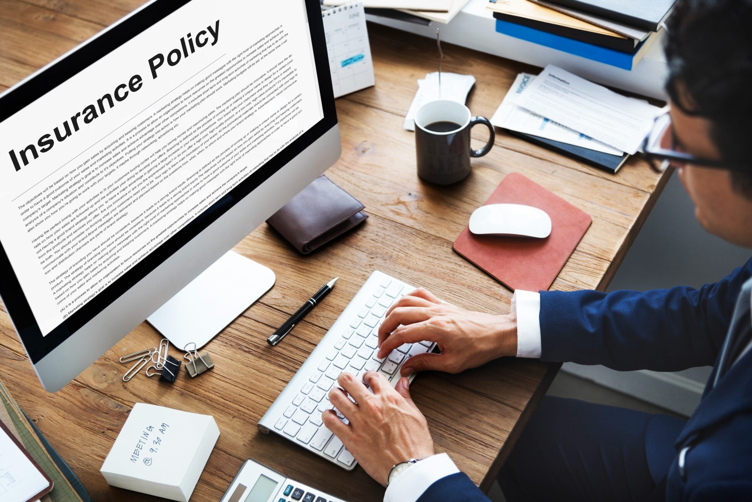 Person typing on a keyboard with an insurance policy displayed on a computer screen, symbolizing insurance verification in healthcare revenue cycle management.