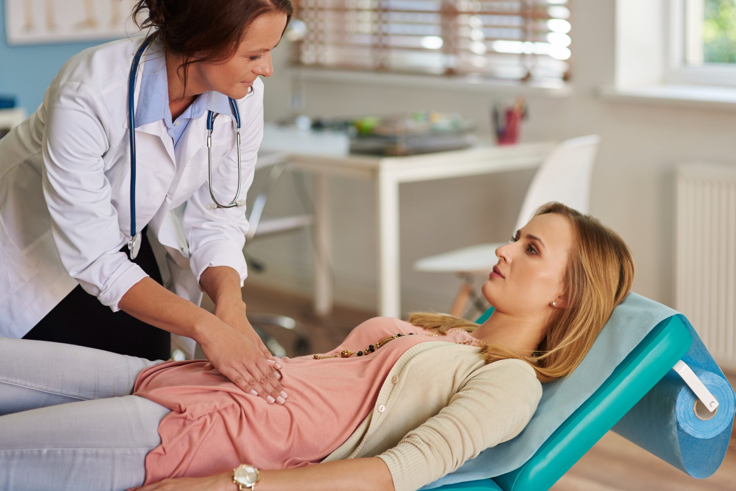 Doctor examining a patient’s abdominal area in a clinical setting, focusing on patient comfort and care