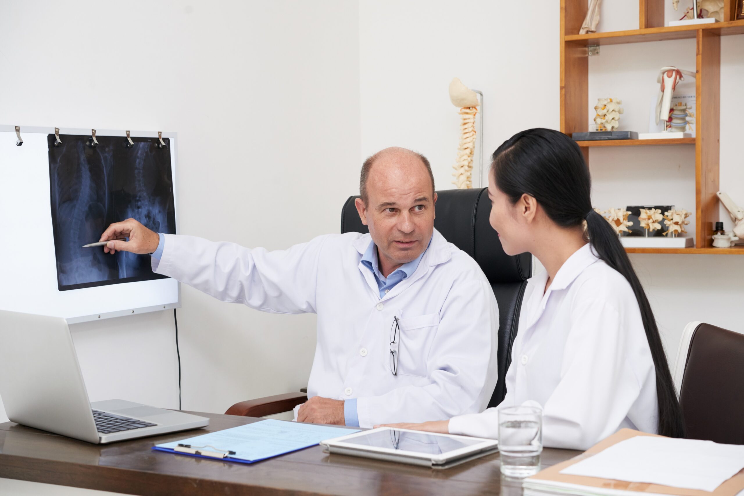 Doctor explaining X-ray to colleague during prior authorization discussion.