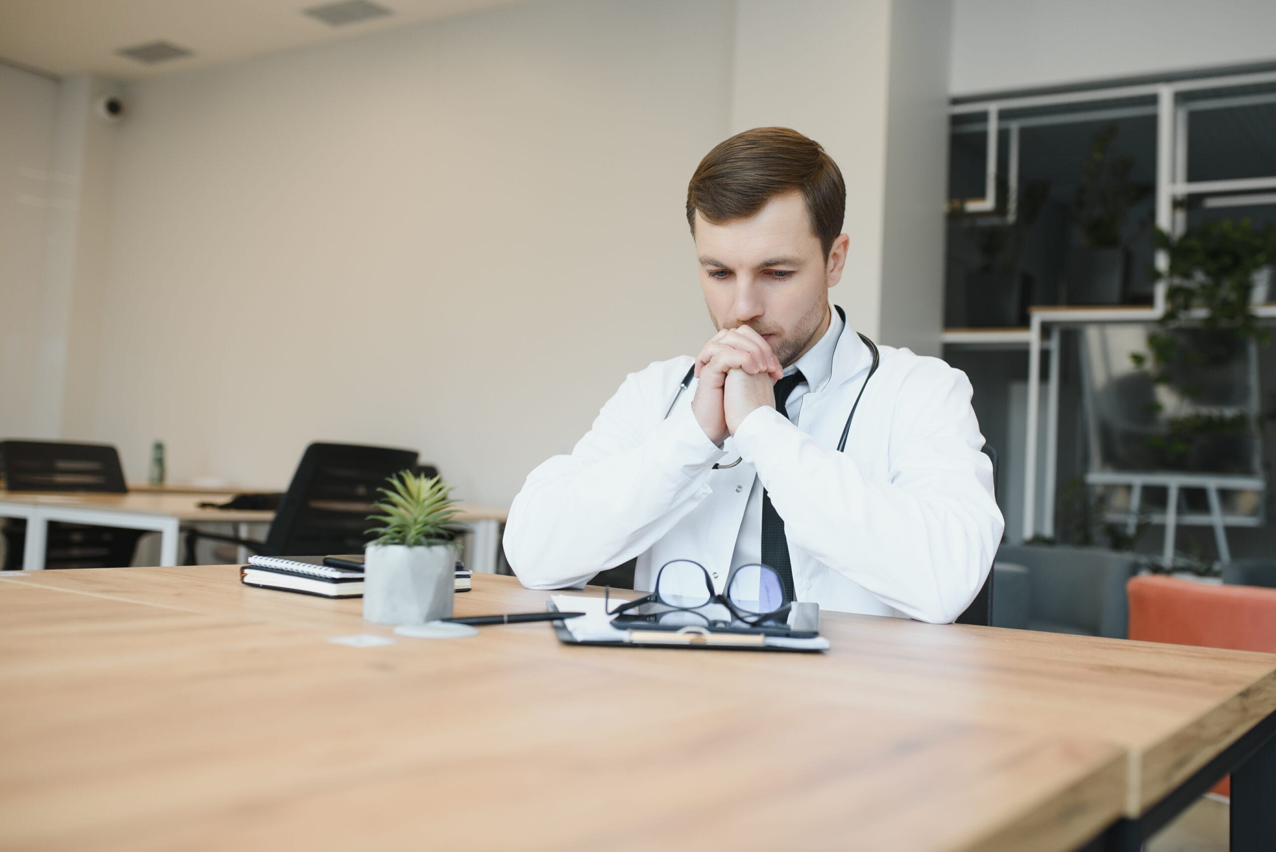 A physician smiling while consulting with a patient, supported by a virtual medical scribe.