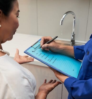 Healthcare professional discussing medical billing or insurance information with a patient, using a clipboard to document details