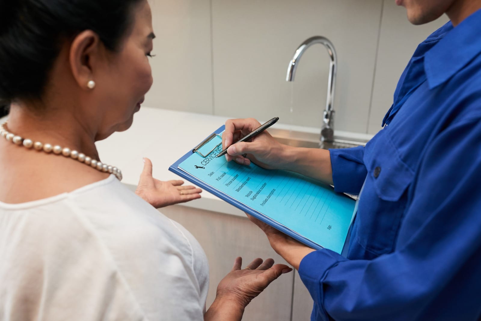 Healthcare professional discussing medical billing or insurance information with a patient, using a clipboard to document details