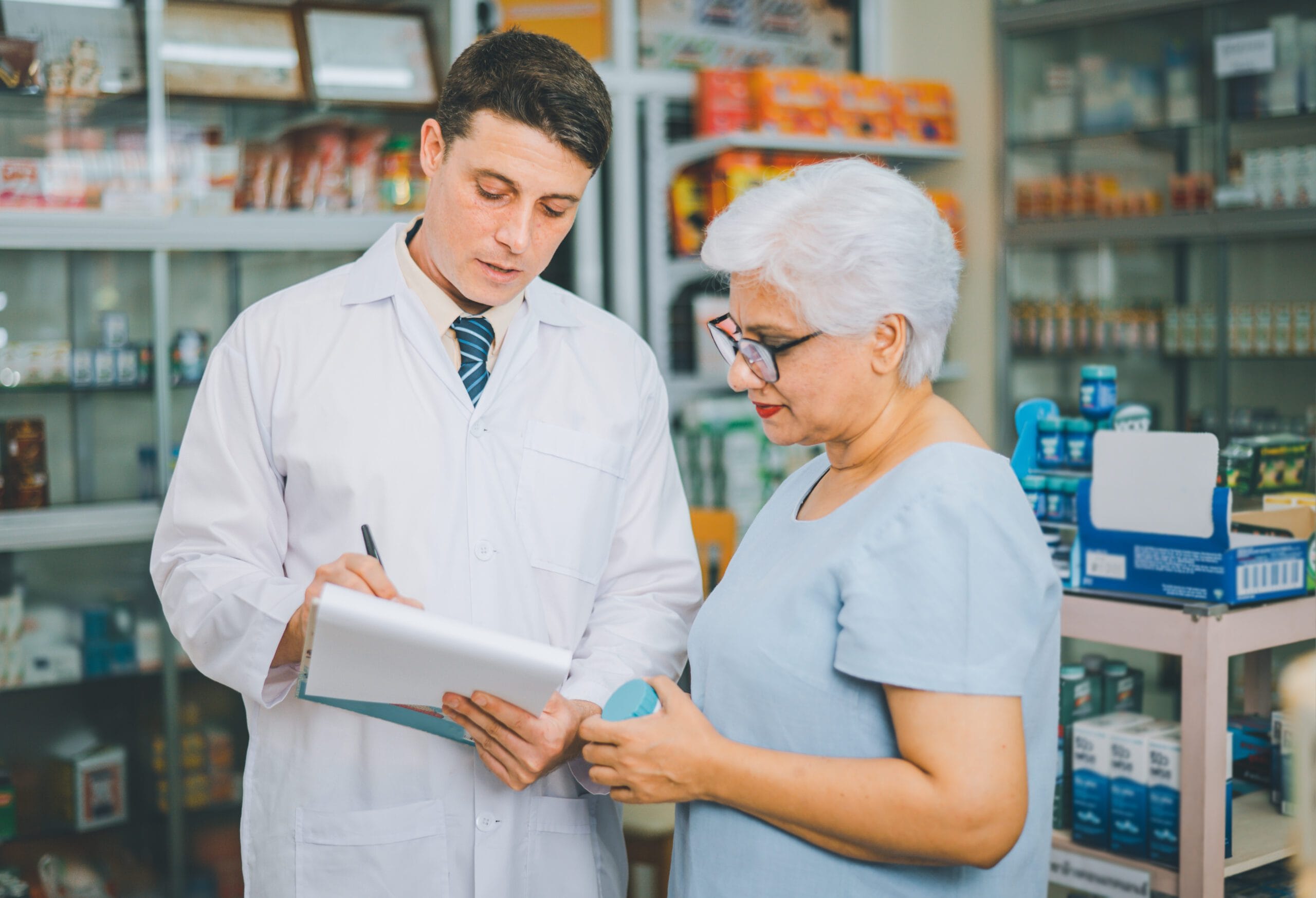 A pharmacist discussing medication with an elderly woman in a pharmacy setting, representing personalized care and billing accuracy.