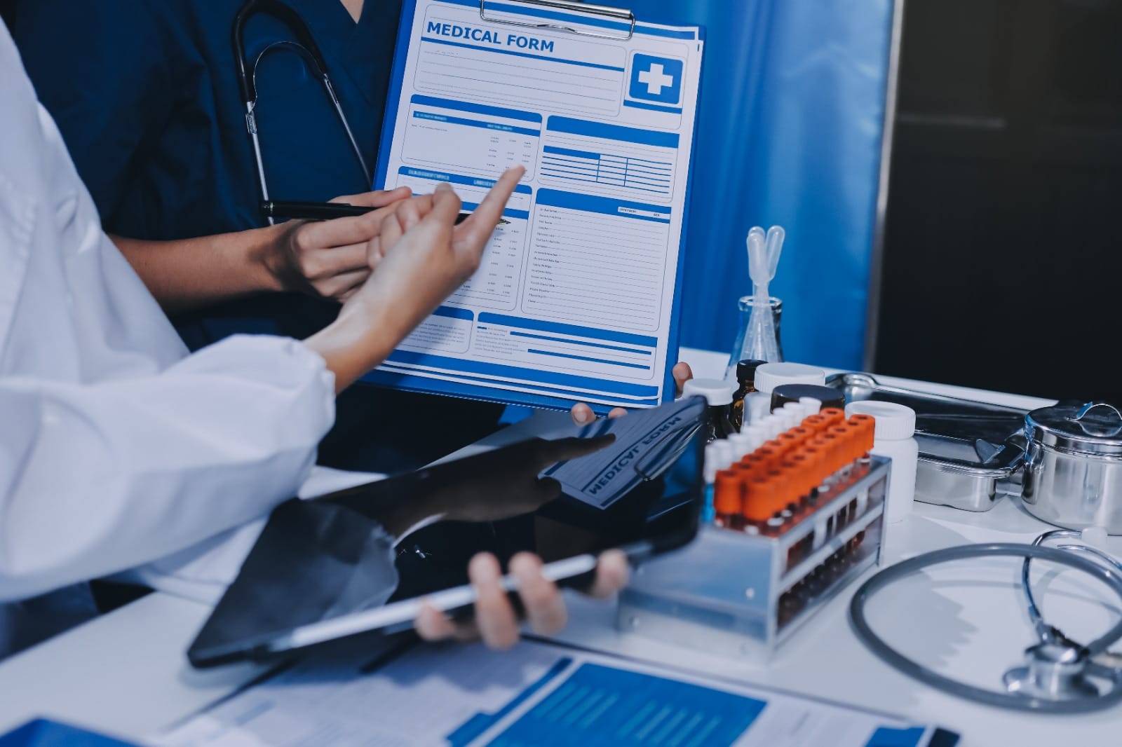 Healthcare professionals reviewing a medical form with lab samples and medical tools on a desk, symbolizing accuracy and efficiency in medical coding.