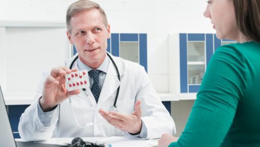 Doctor explaining medication and prior authorization requirements to a patient in a clinical setting.