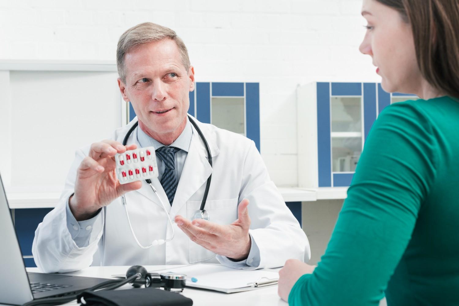 Doctor explaining medication and prior authorization requirements to a patient in a clinical setting.