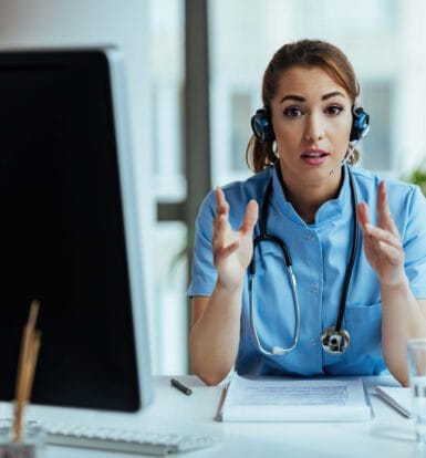 Alt Text: Female healthcare professional wearing a headset and explaining telemedicine outsourcing benefits during a virtual consultation.