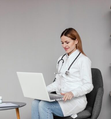 Doctor using a laptop for administrative tasks in a medical office, representing the role of virtual medical assistants vs in-house staff.