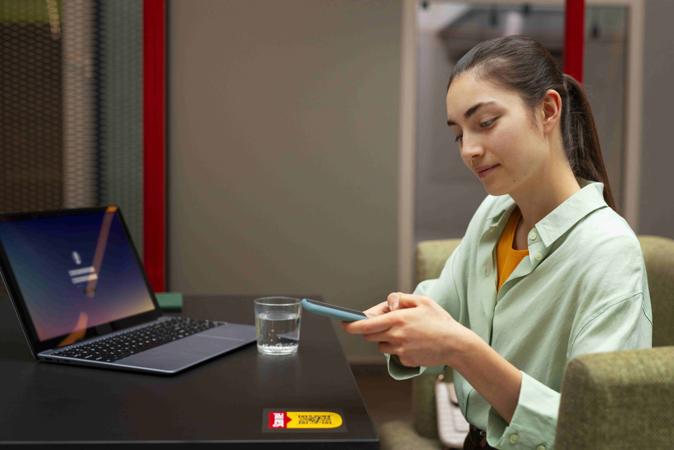 A healthcare professional using a smartphone and laptop to manage telemedicine outsourcing tasks efficiently.