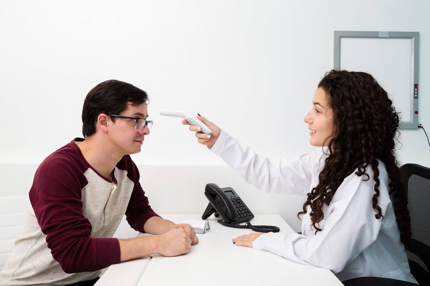 A healthcare provider using a medical device to assess a patient’s health during a consultation for Omnitrope prior authorization.