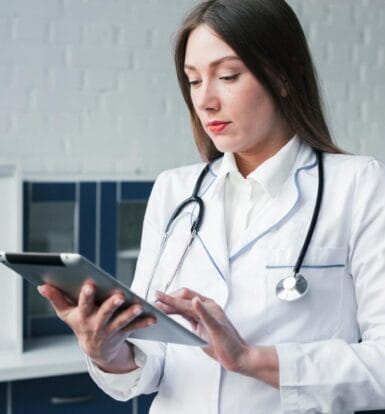 A healthcare provider using a tablet to manage patient data, representing the efficiency of outsourcing Virtual Assistants for practice management.