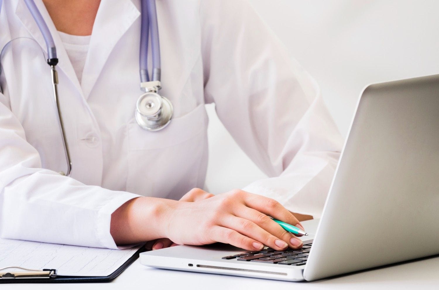 Doctor using a laptop to manage medical billing and coding tasks, showcasing a streamlined workflow.