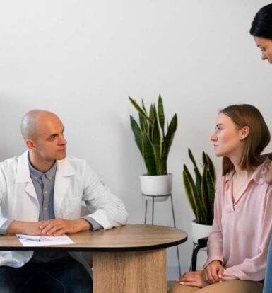 A doctor consulting with a young female patient and her caregiver, symbolizing the collaborative process of securing prior authorization for medications like Rexulti.