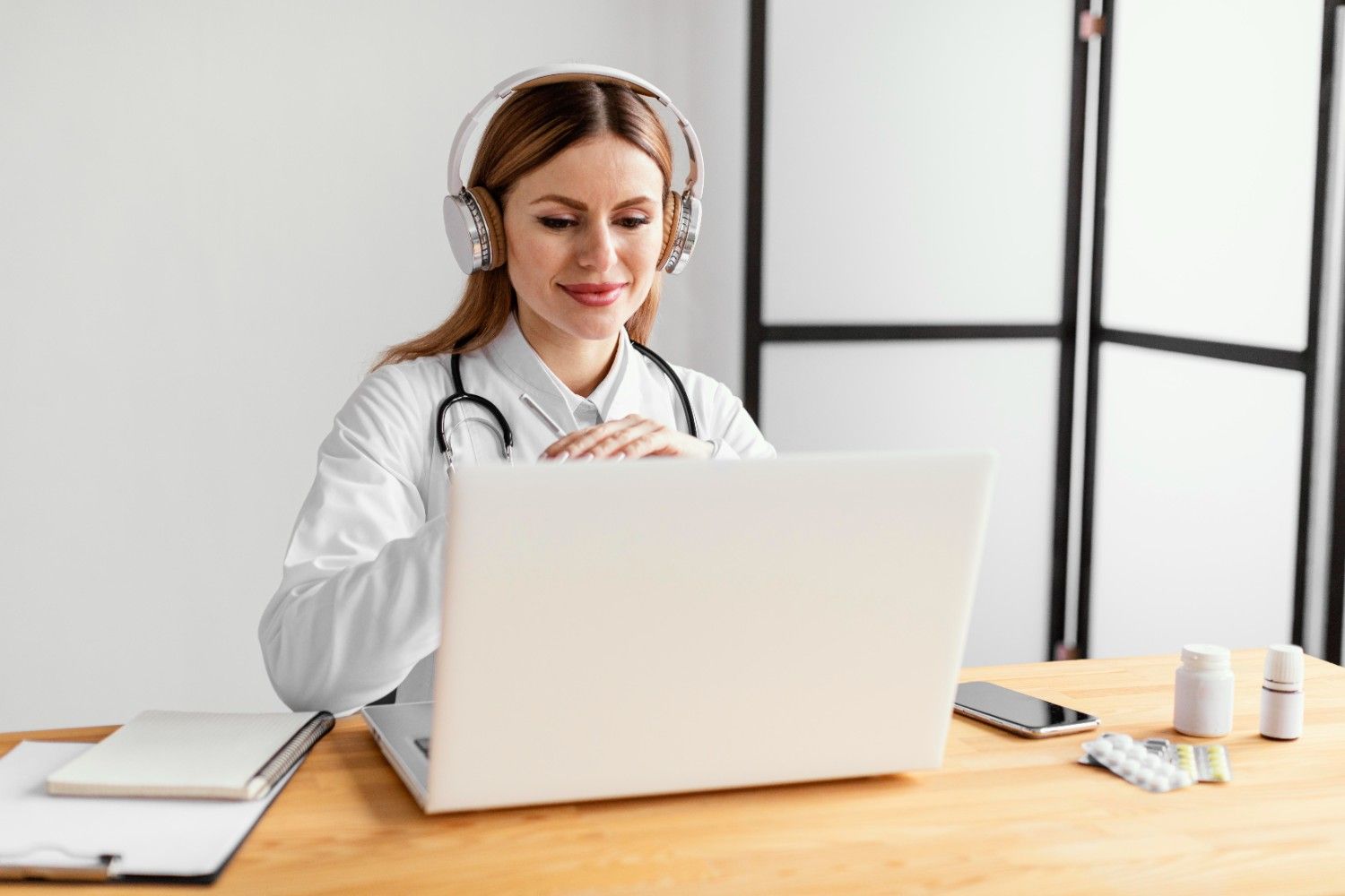 Doctor with headphones working on a laptop, representing a virtual medical assistant helping with healthcare administration.