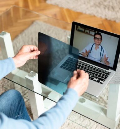 Virtual healthcare consultation with a doctor on a laptop screen and a patient holding medical scans.