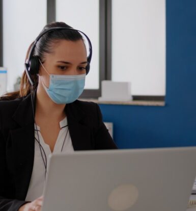 A healthcare provider smiling while reviewing a report on a tablet, assisted by a Virtual Medical Assistant remotely.