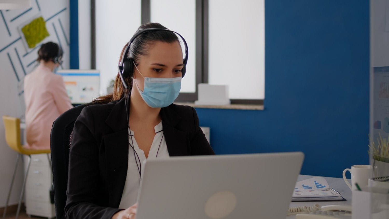 A healthcare provider smiling while reviewing a report on a tablet, assisted by a Virtual Medical Assistant remotely.