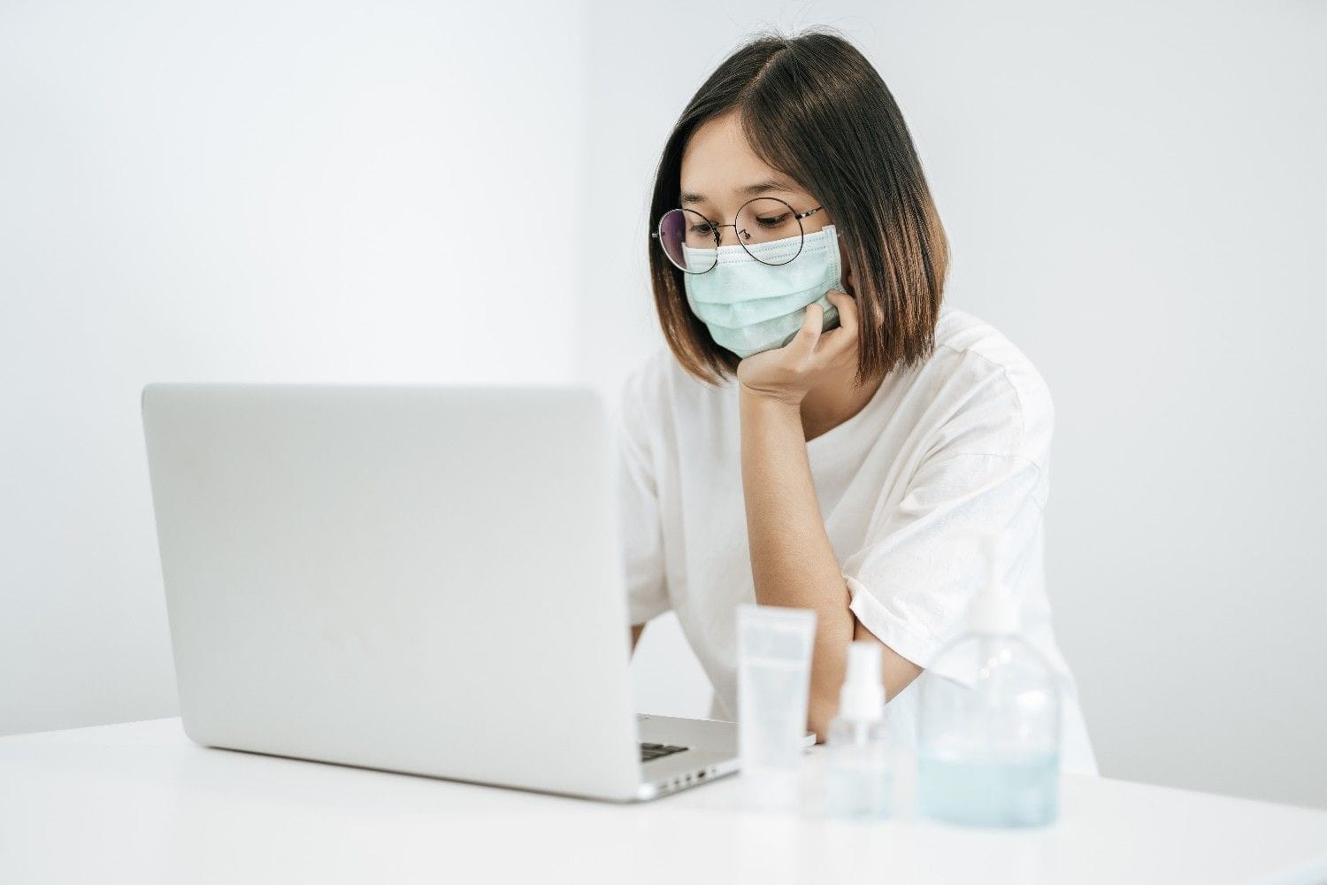 A healthcare professional wearing a mask and working on a laptop, showcasing secure and efficient virtual communication in healthcare.