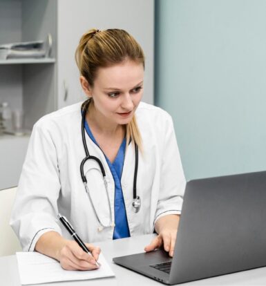 Doctor wearing a stethoscope, working on a laptop while taking notes, demonstrating secure handling of patient information.