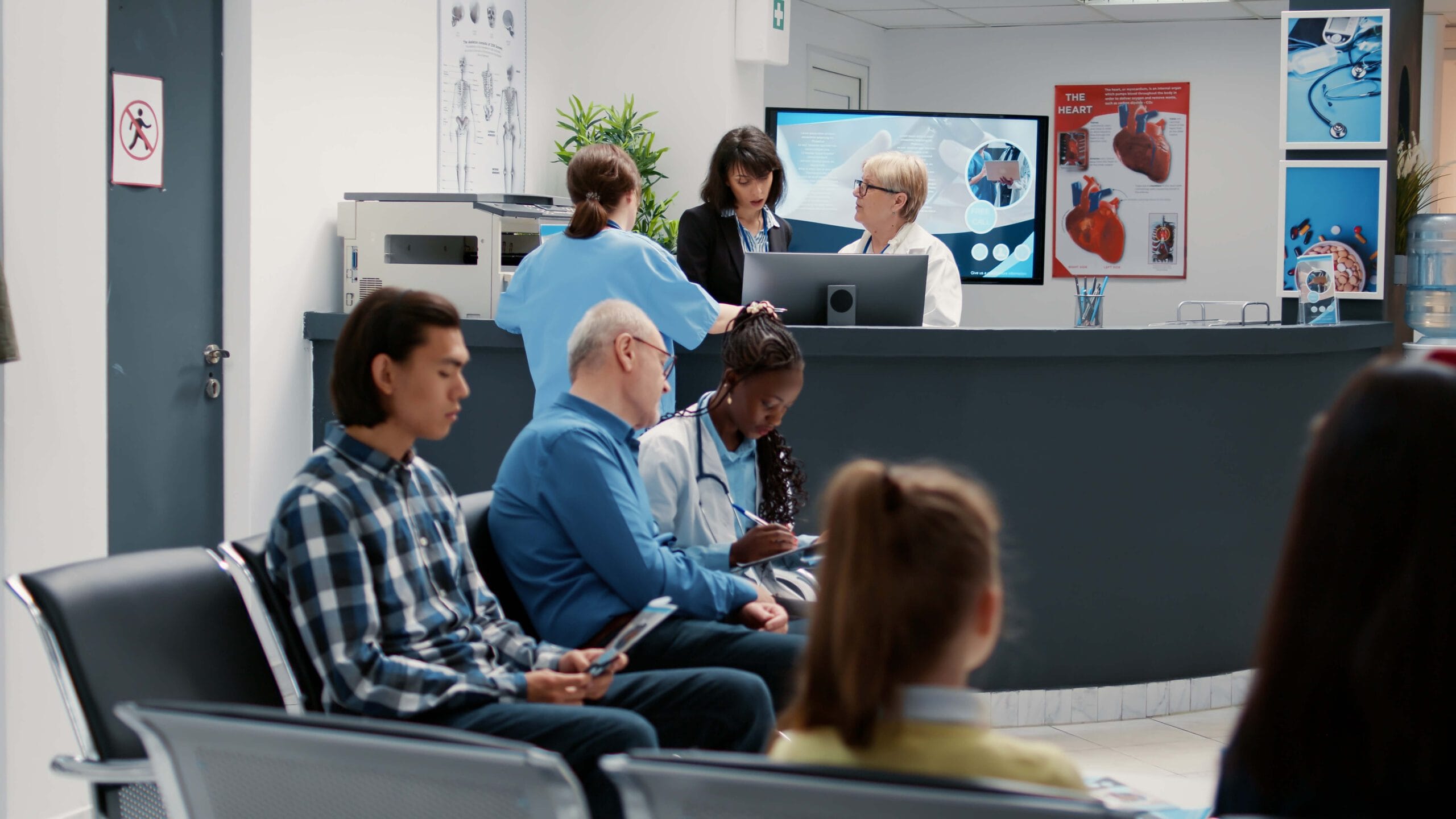 A busy hospital waiting area with patients seated, nurses reviewing files, and administrators working at the reception desk, symbolizing the role of telemedicine outsourcing in improving patient care and operational efficiency.