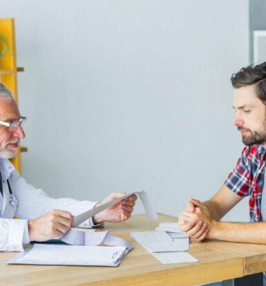 Doctor reviewing prior authorization paperwork with a patient in a clinical setting.