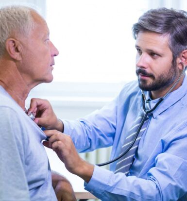 A healthcare provider using a stethoscope to examine a male patient during a consultation, emphasizing personalized prostate cancer care.