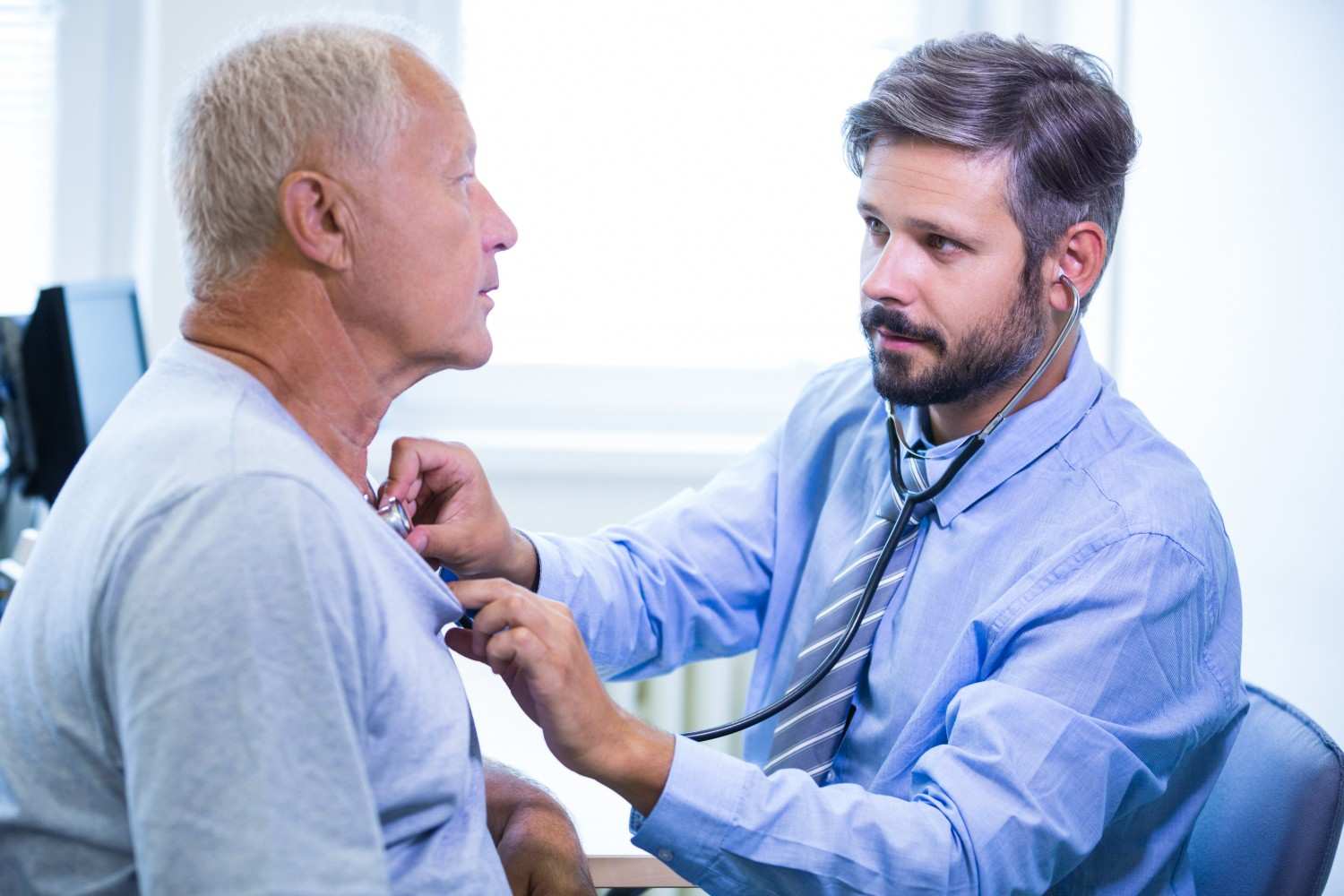 A healthcare provider using a stethoscope to examine a male patient during a consultation, emphasizing personalized prostate cancer care.