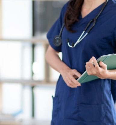 A medical scribe securely documenting a patient encounter on a laptop in a clinic setting.