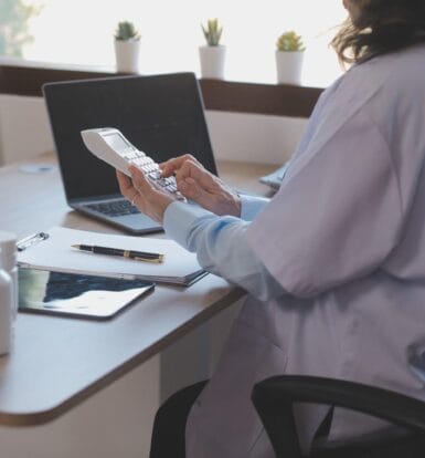 A medical coder working on a secure computer with coding manuals.