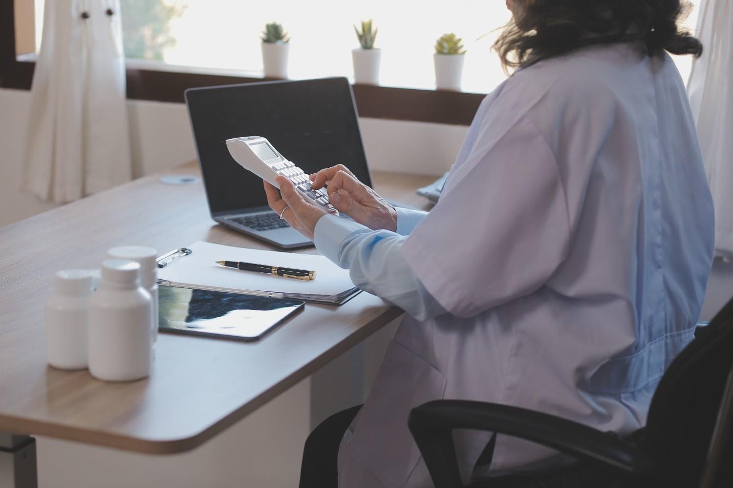 A medical coder working on a secure computer with coding manuals.