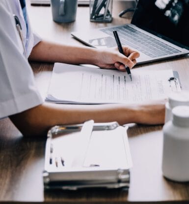 A medical coder working on a secure computer system with patient data.