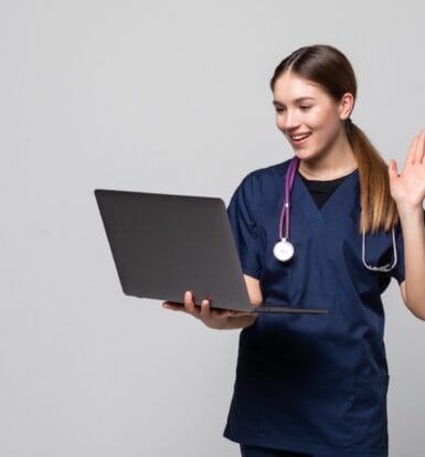 Virtual Medical Assistant waving while working on a laptop, providing remote healthcare support.